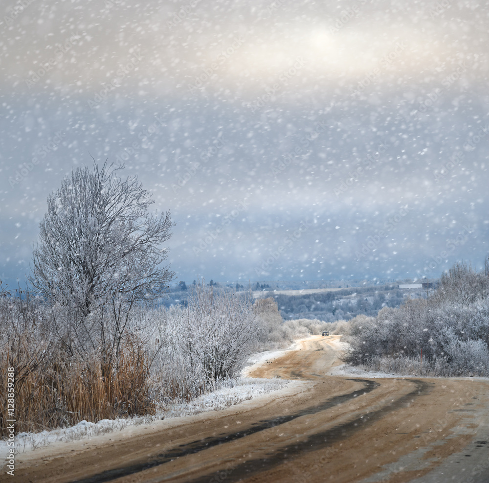 雪和阳光透过乡村道路上的云层照耀。