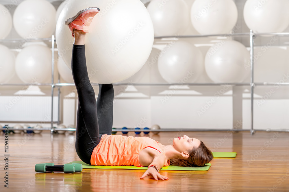 Young woman making exercise with fitball in the fitness room