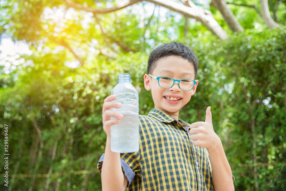 Young asian boy holding drink water bottle in park