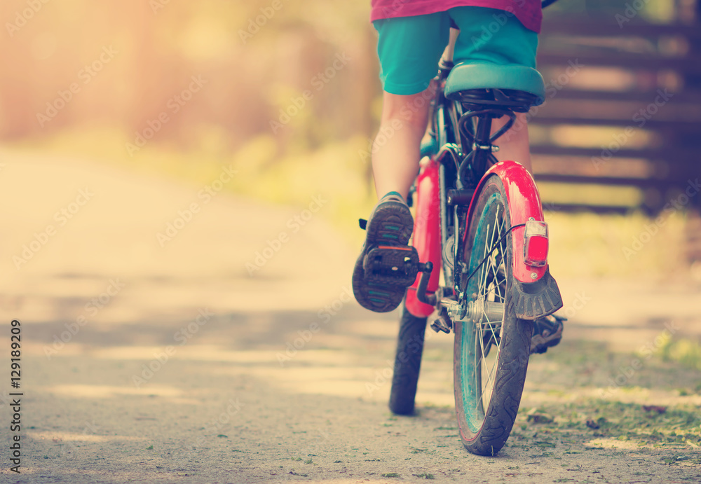 child on a bicycle at asphalt road in early morning