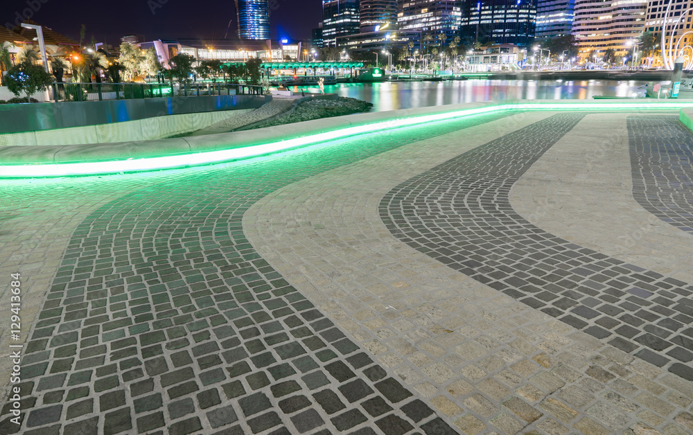 Green neon lights circulating underneath the stone seating reflecting on the stone pavement in Perth