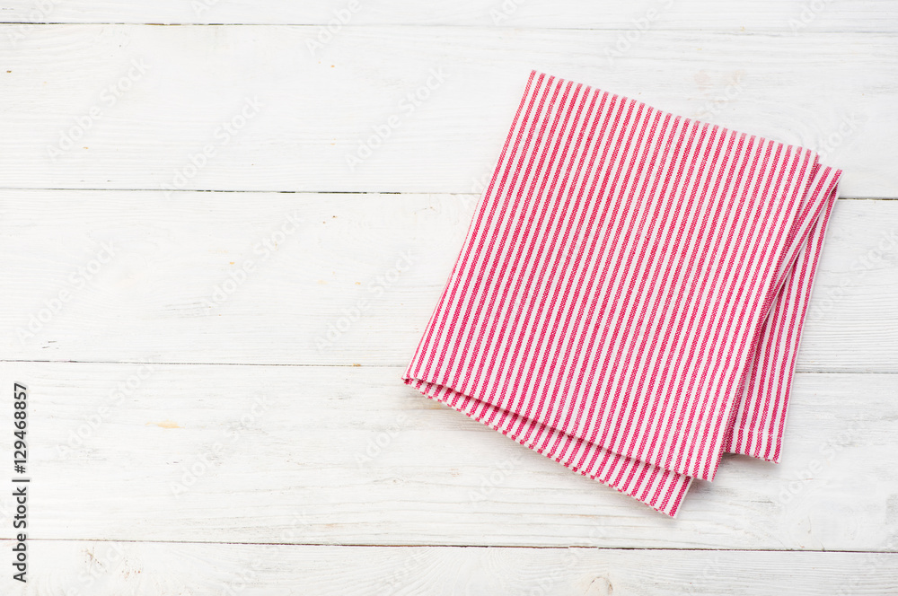 Red rustic napkin isolated on white wooden table. Copy space. Top view.