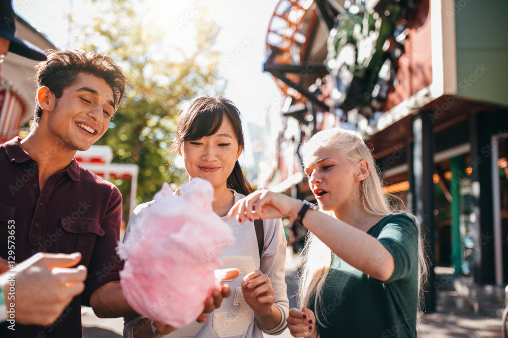 Group of friends eating cotton candy in amusement park