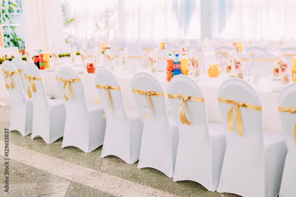 Decorative White Mantles And Colored Ribbons On Chairs At Festive Table.