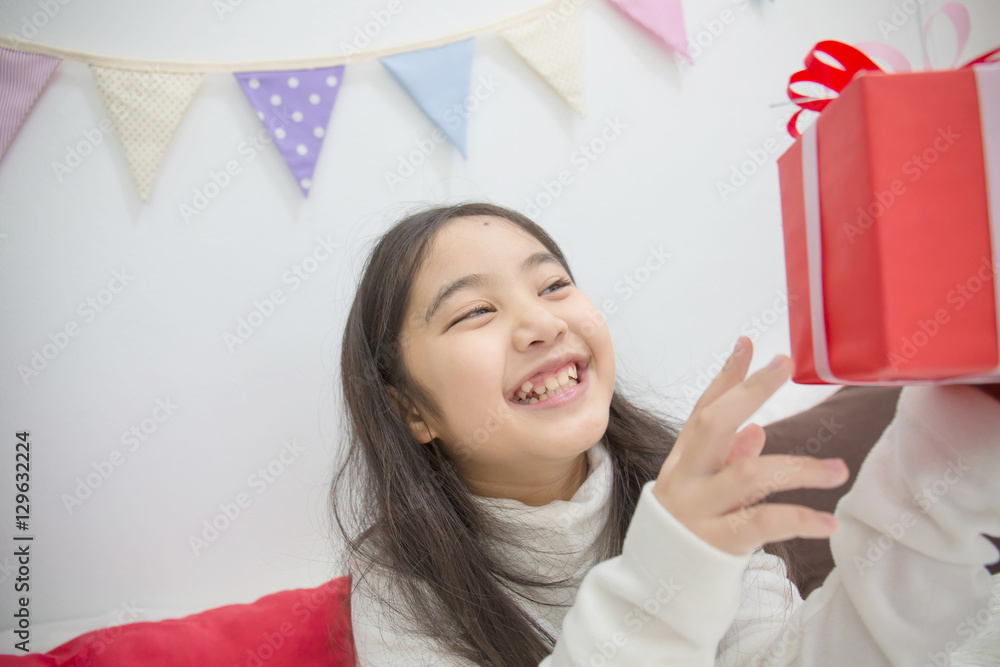 Happy Asian girl shaking a present to guess whats inside