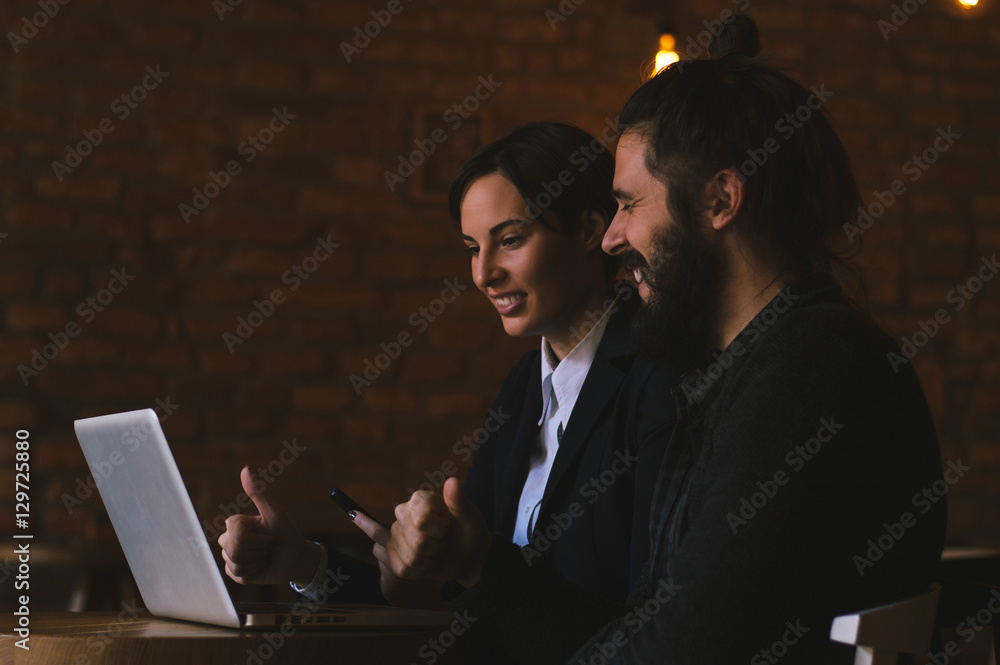 Two Young Businesspeople Working On Laptop In Coffee Shop