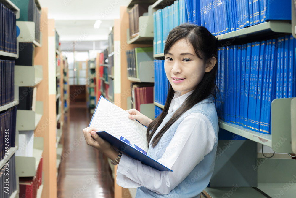 穿着制服的亚洲学生在大学图书馆阅读。