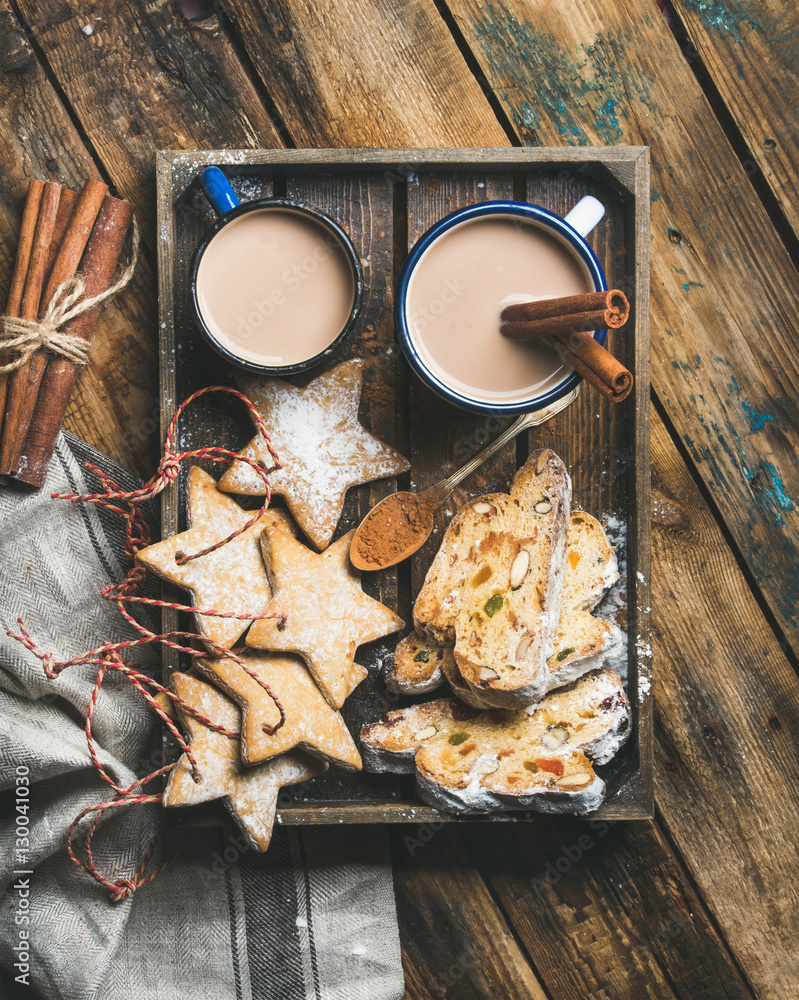 Cocoa in mugs with Christmas gingerbread star shaped cookies, pieces of Stollen cake and spices in w