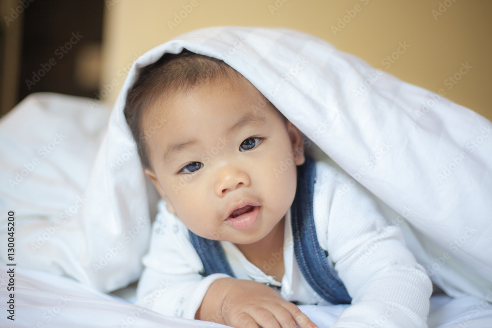 baby boyl is hiding under the white blanket