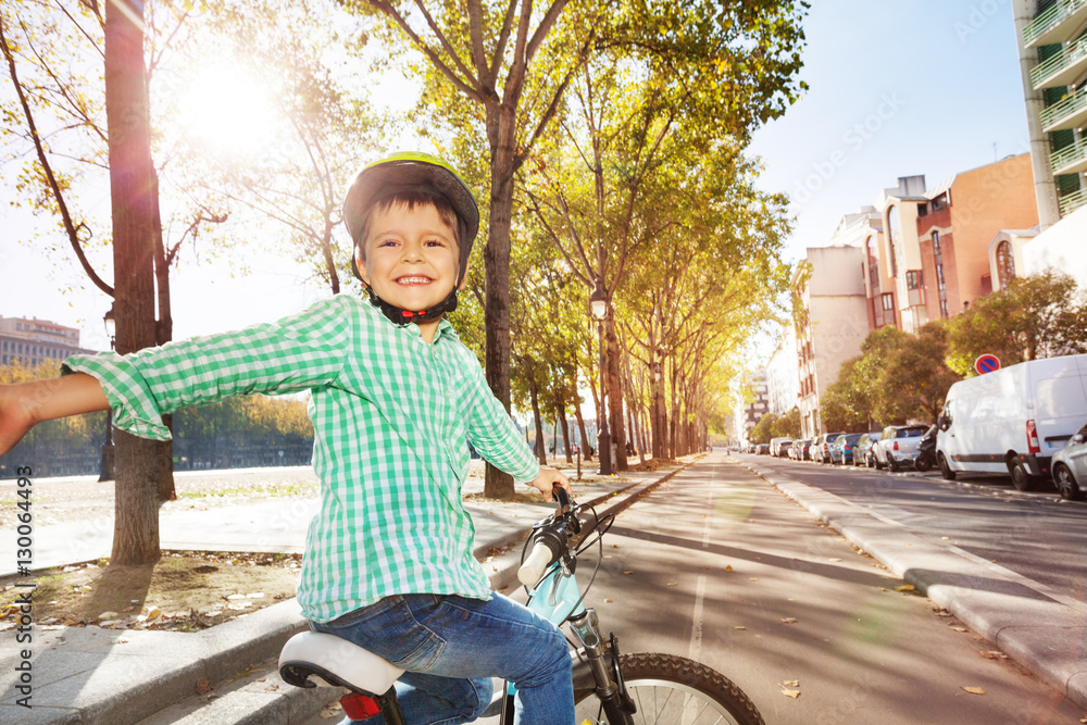 Happy boy cycling on bicycle lane in town