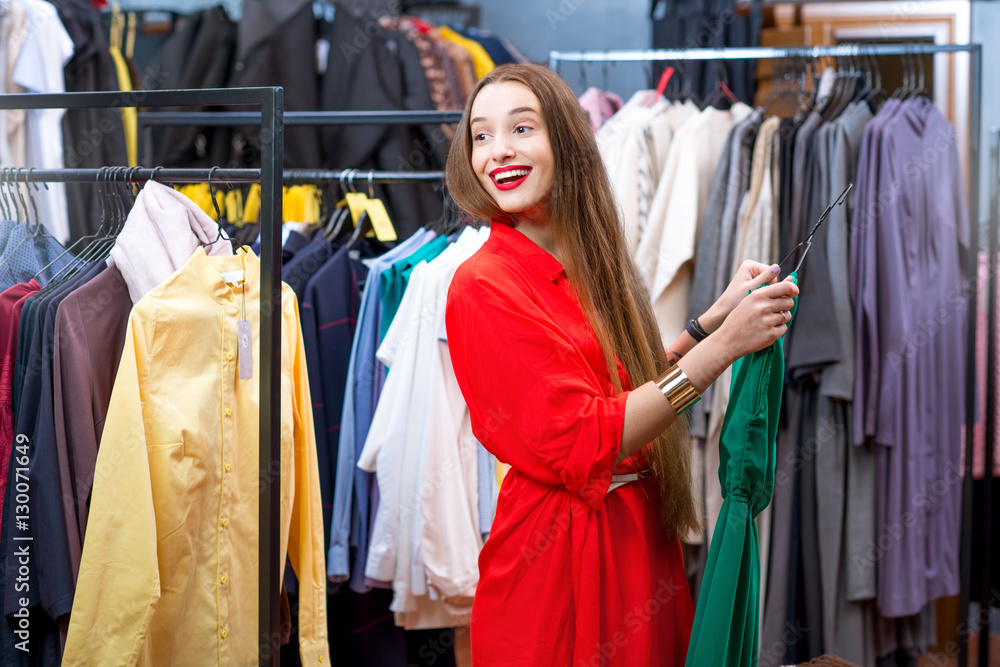 Young woman in the red dress shopping in the luxury clothing store