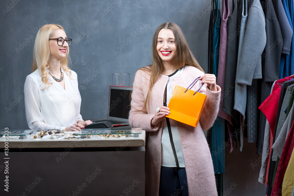 Happy woman buying clothing accessories at the paydesk with cashier in the clothing store