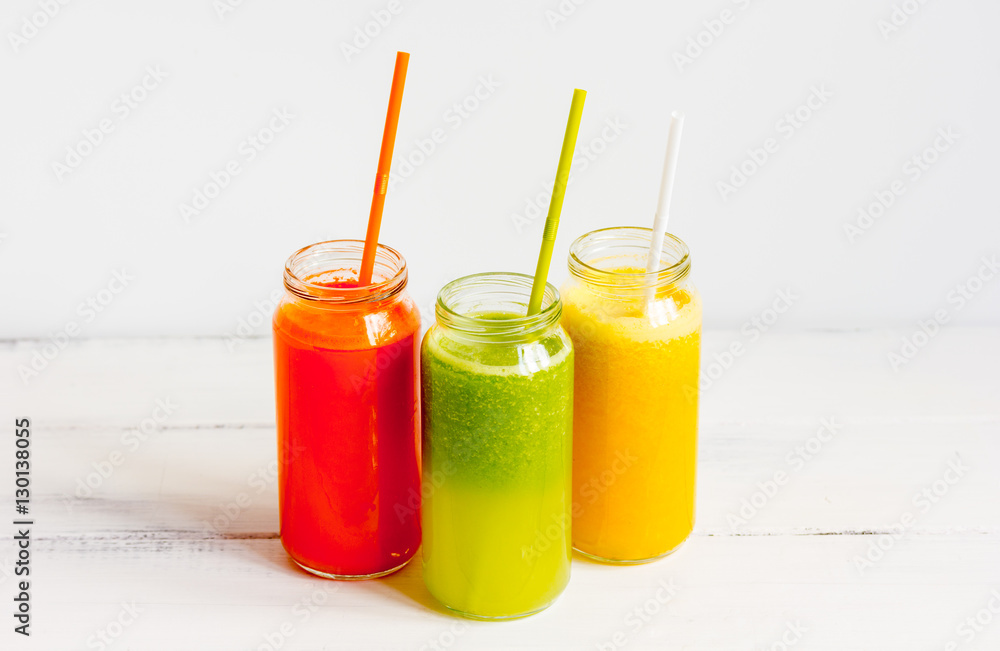 Fresh detox juices in glass bottles on white background