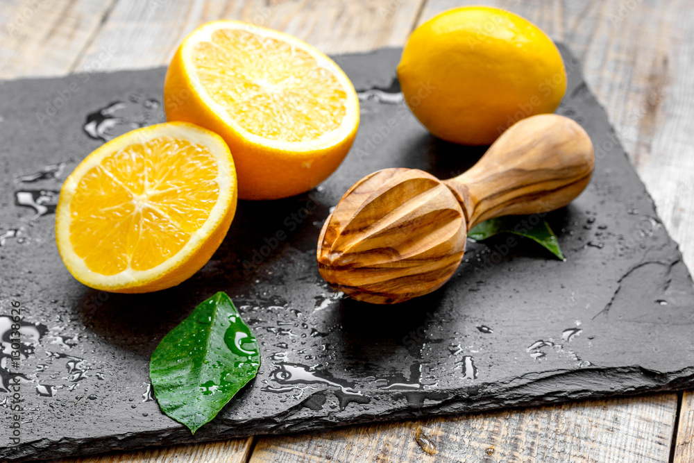 cut oranges in half and juicer on wooden background