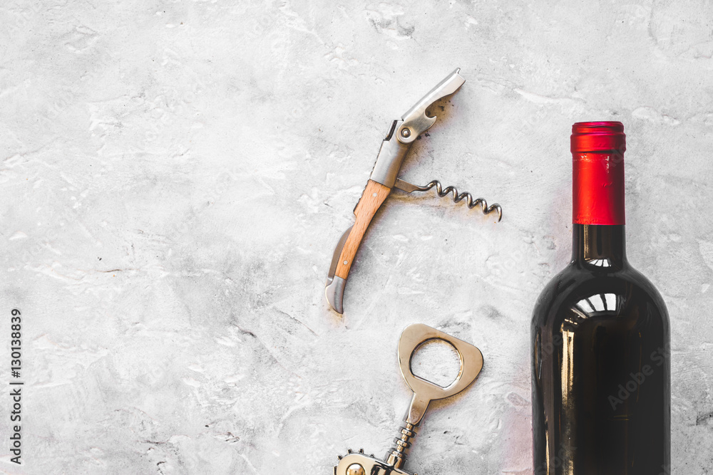 glass wine bottle and corkscrew on concrete background top view