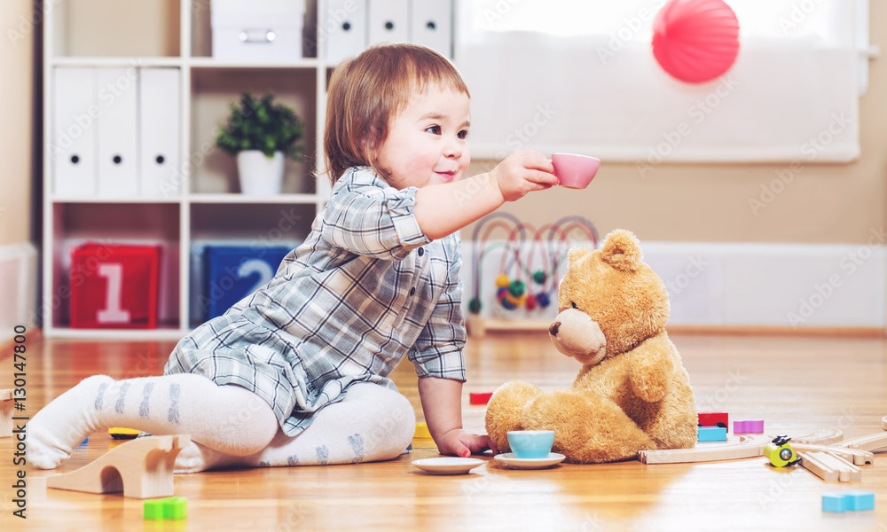 Happy toddler girl playing with her teddy bear