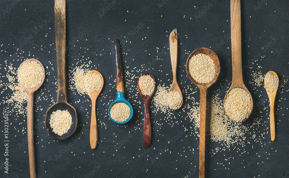 Quinoa seeds in different spoons over black stone background, top view. Superfood, healthy eating, d