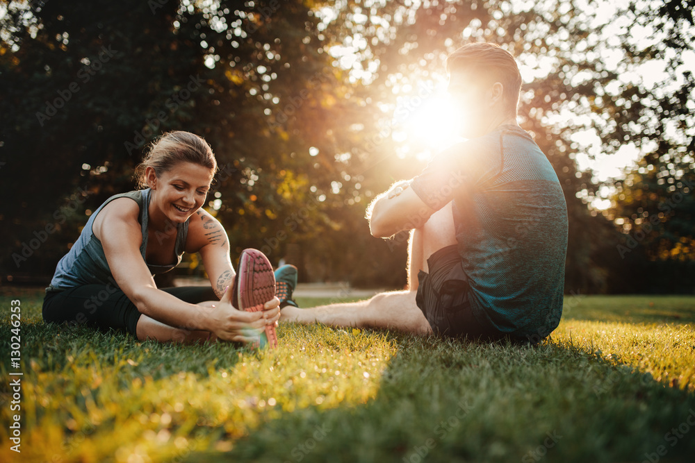 Couple doing stretching exercises in park