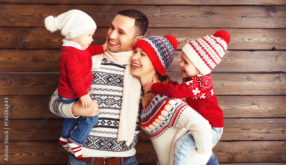 happy family mother, father and children in winter hats on woode