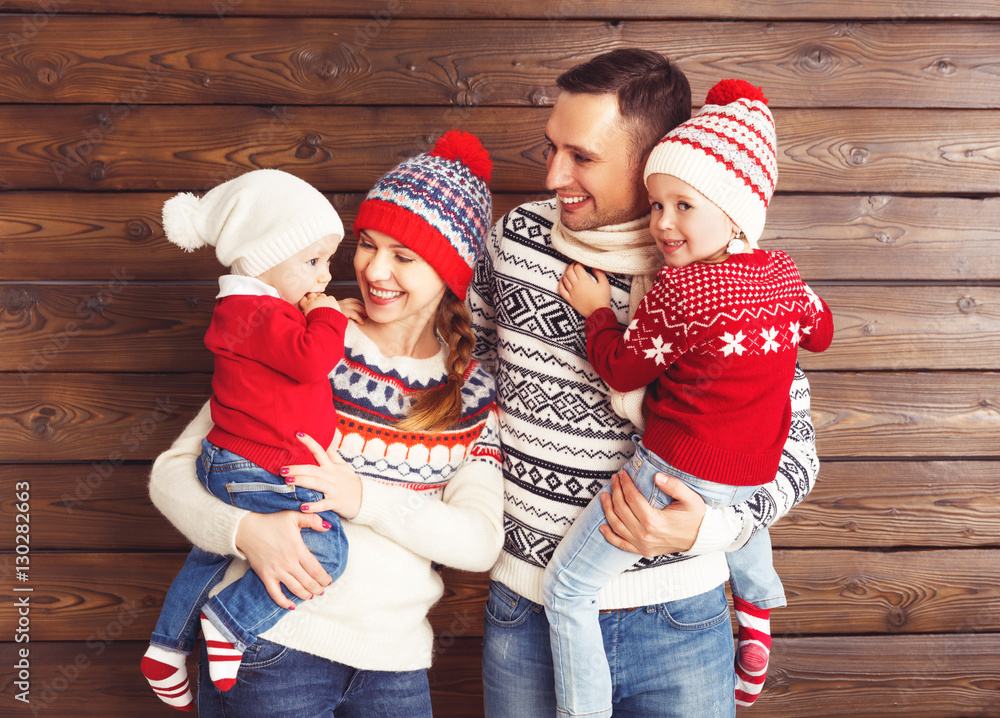 happy family mother, father and children in winter hats on woode