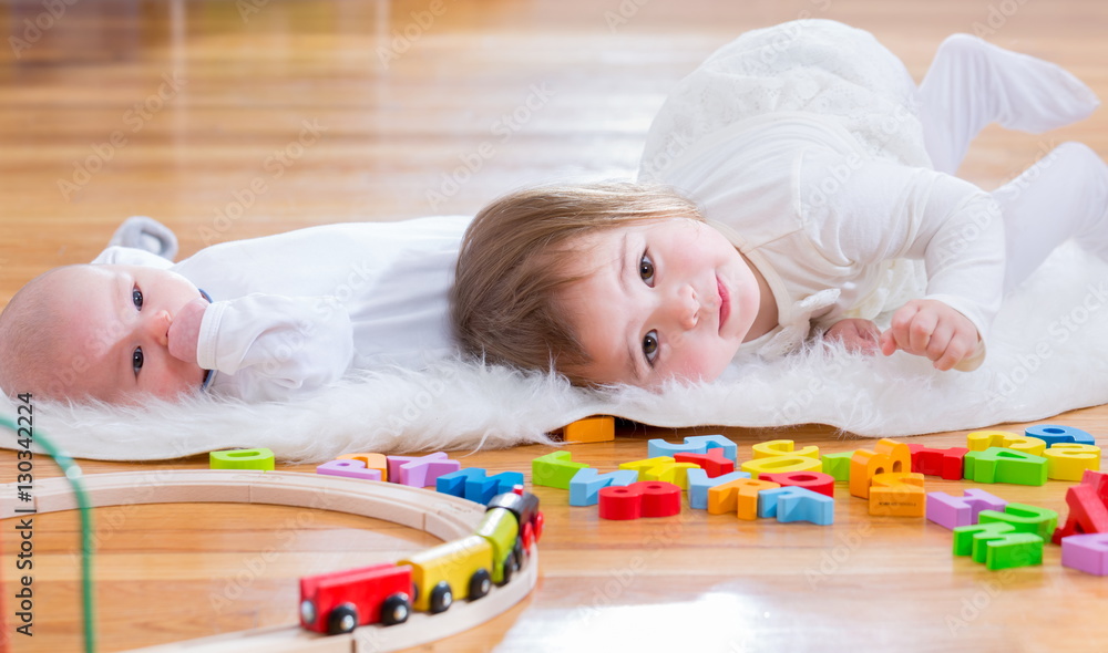 Happy toddler girl playing with her baby sister