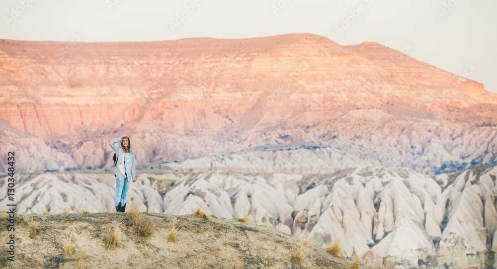 Young woman traveller hiking in the mountains among natural rocks of Cappadocia, Central Turkey. Con