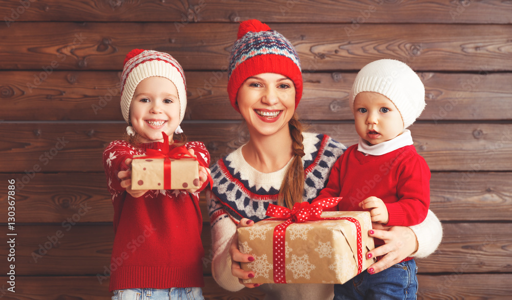 happy family mother and children with christmas gift at wooden b