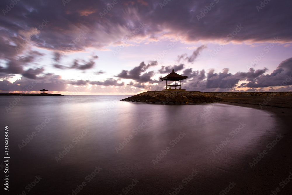 Balinese beach at sunrise with a little temple. Indonesia.