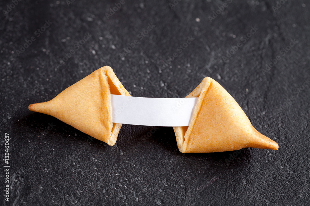 Chinese fortune cookie with prediction on dark background top view