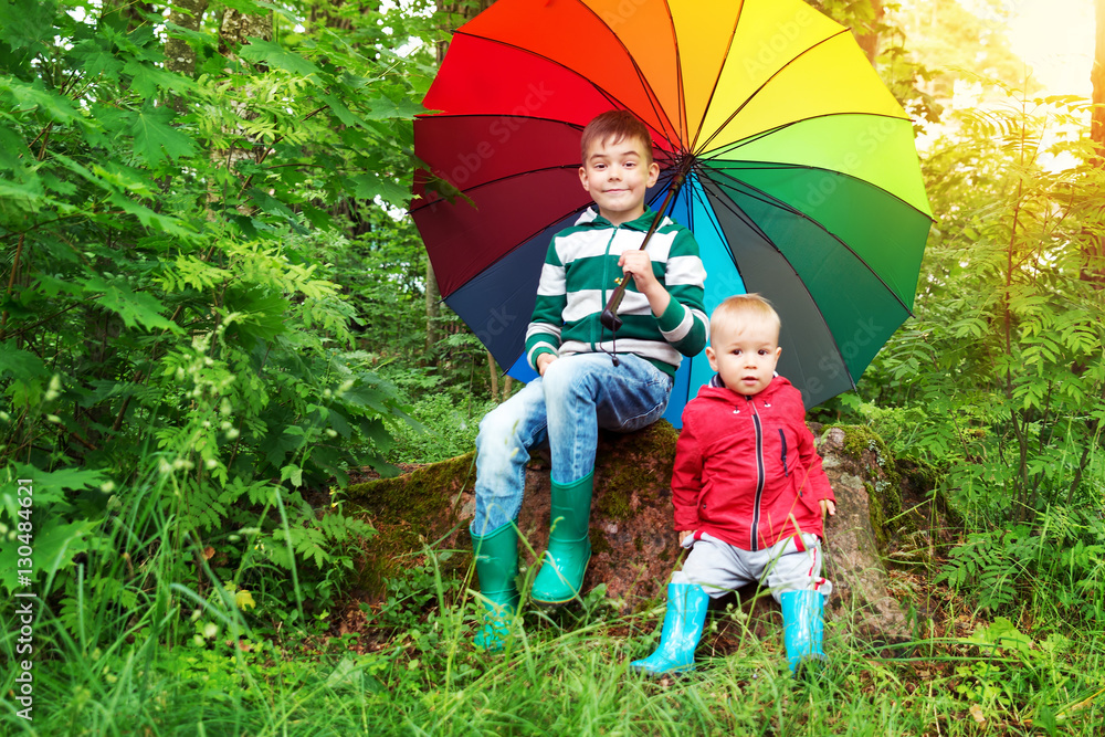 带着五颜六色的雨伞坐在公园里的孩子