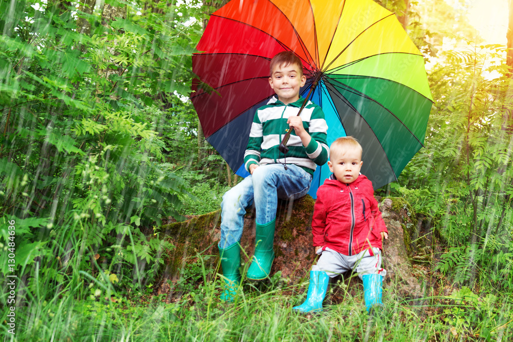 Children sitting in the park with colourful umbrella