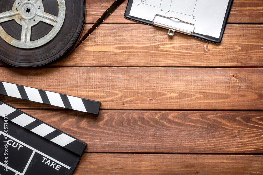 Screenwriter desktop with movie clapper board wooden background top view