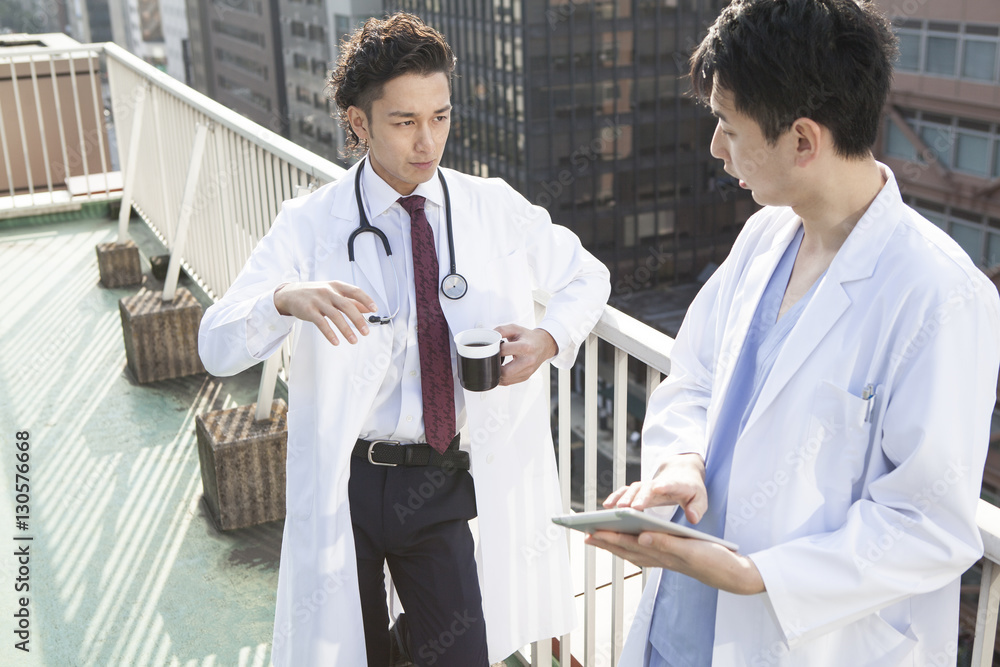 Two doctors are talking on the rooftop during a break