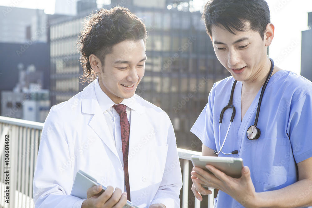 Two young doctors are watching electronic tablet on the hospitals rooftop