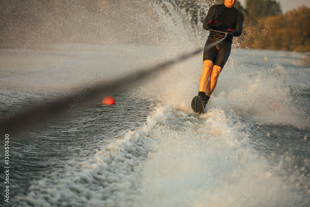 Man riding wakeboard on wave of motorboat