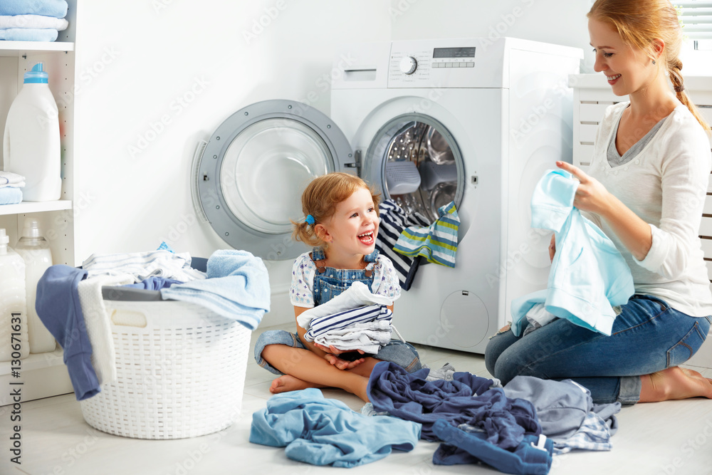 family mother and child girl  in laundry room near washing machi