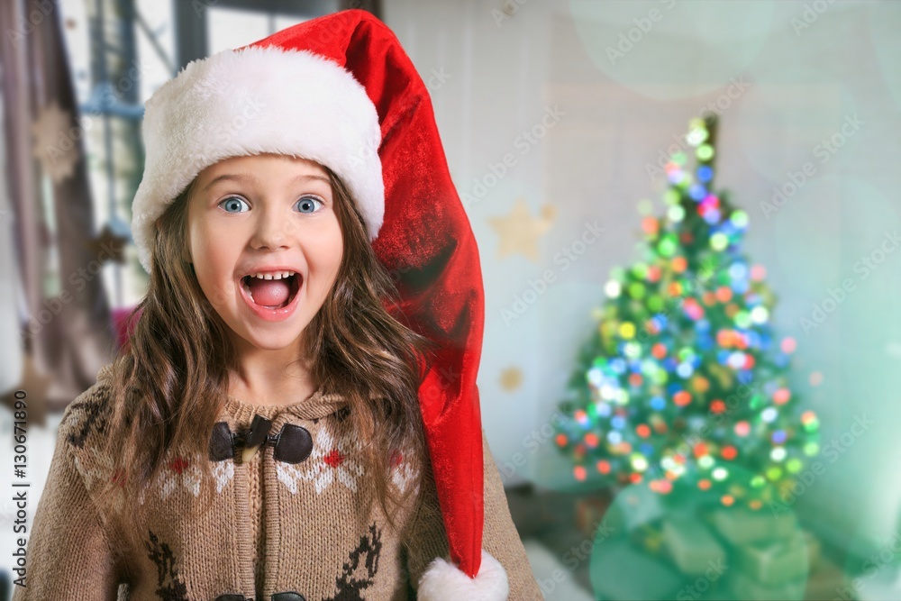 Happy child girl in a christmas hat.