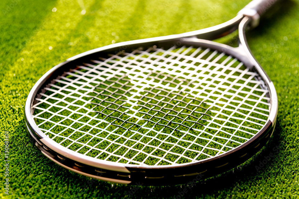 tennis racket on green background close up