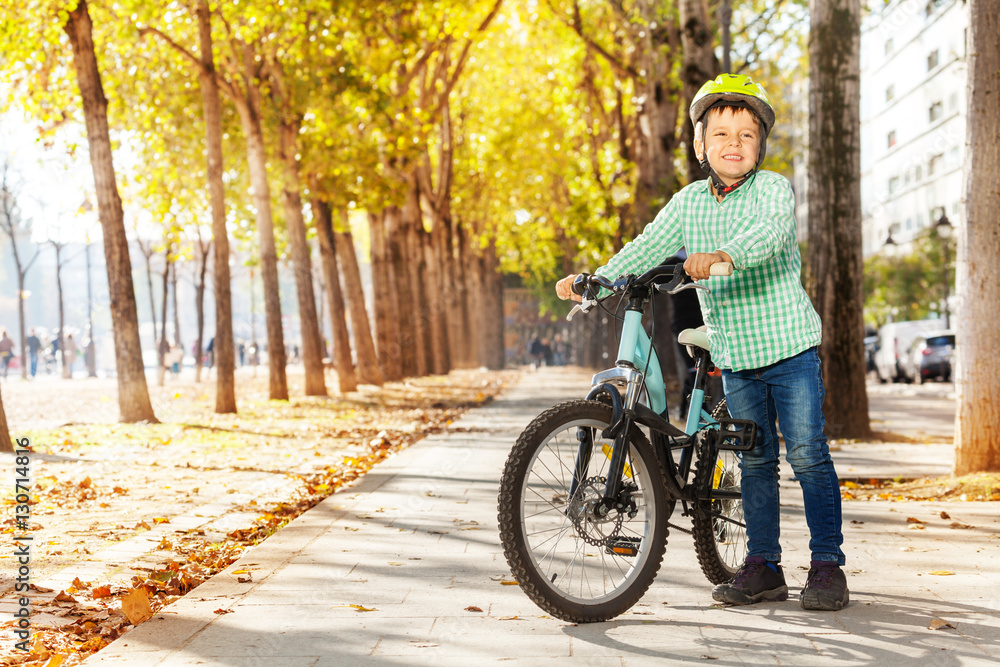 Smiling boy with his bike at autumn park