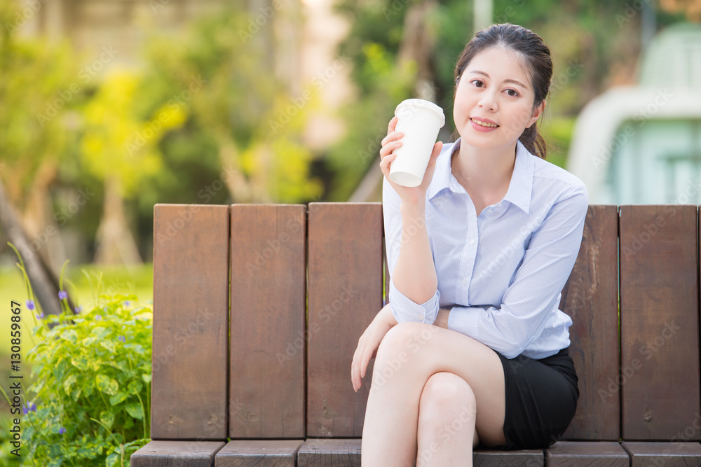 beautiful asian business woman drinking coffee on park bench