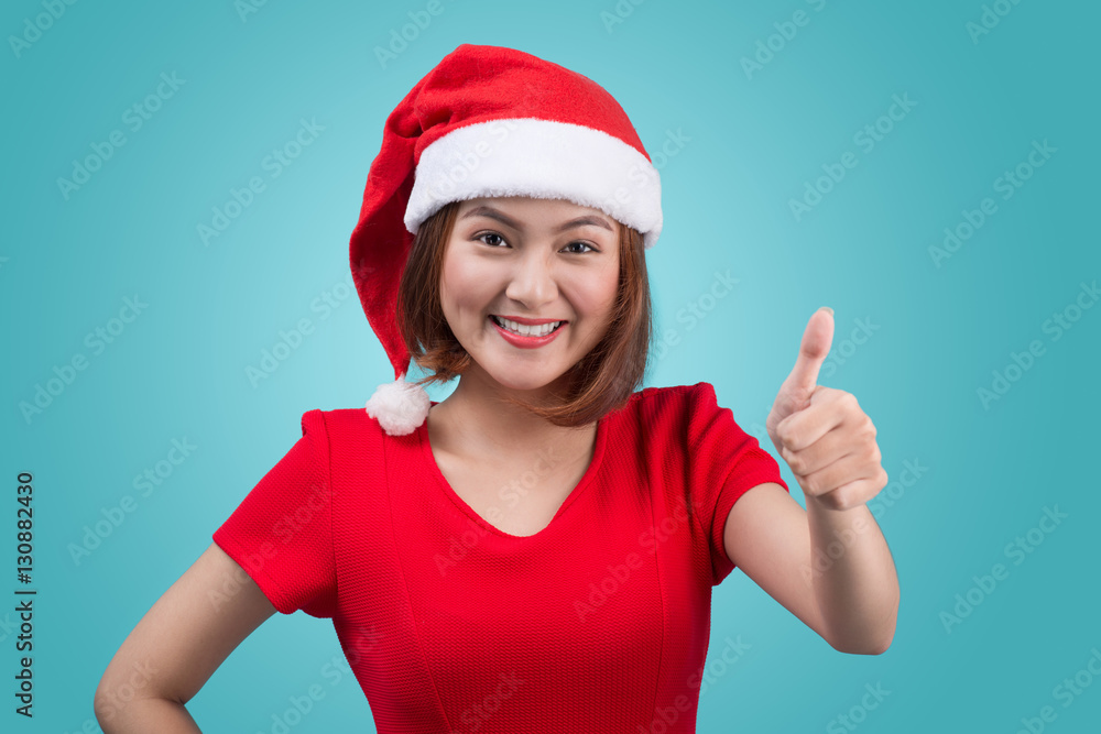 Smiling asian woman portrait with christmas santa hat isolated on blue background.