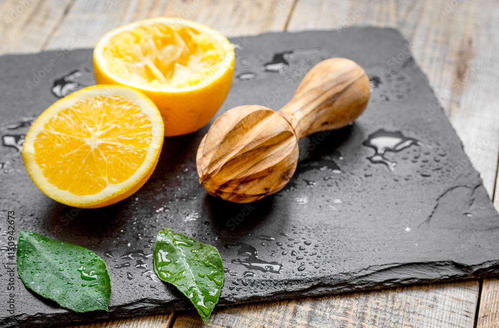 cut oranges in half and juicer on wooden background