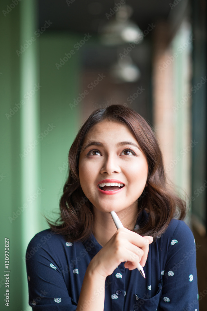 Young beautiful woman in the cafe near the window, thinking and writing something.