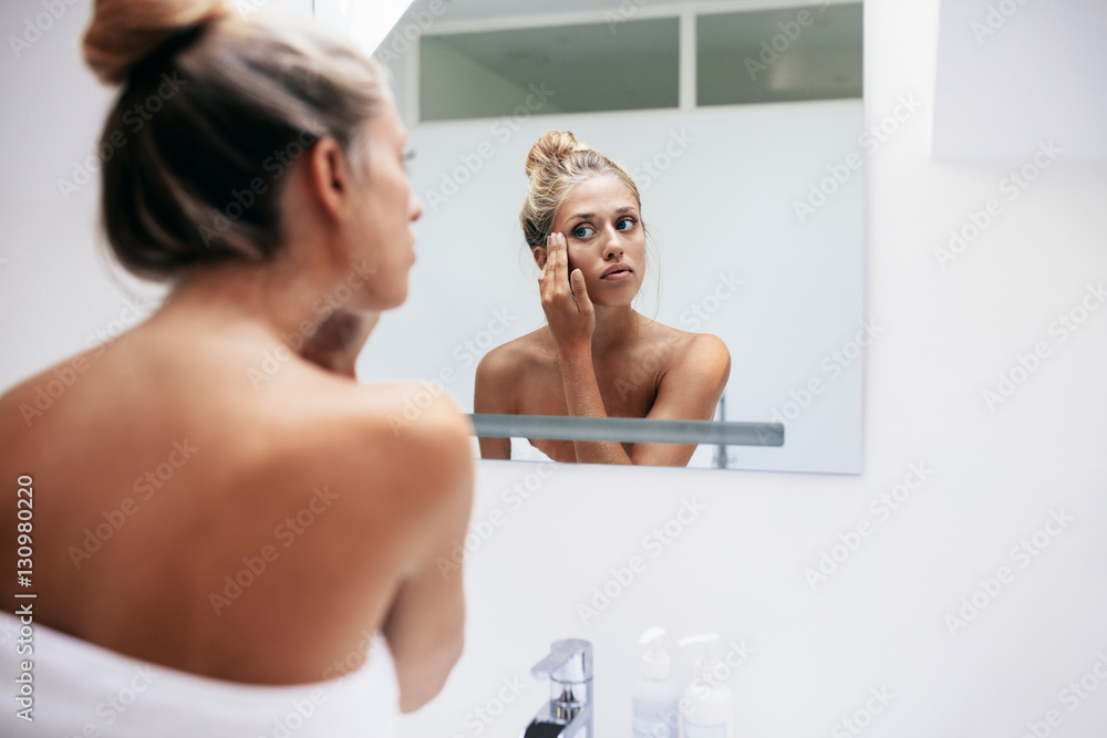 Woman applying cosmetic cream on face