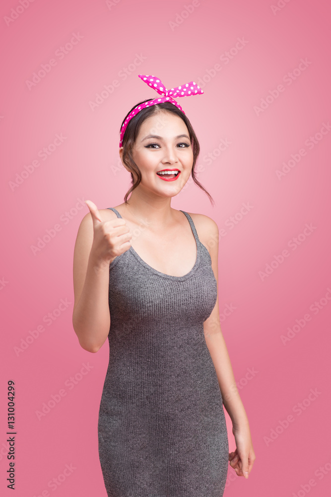 Beautiful asian girl with pretty smile in pinup style on pink ba