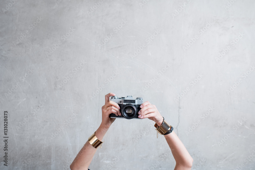 Female hands holding retro photo camera on the gray wall background