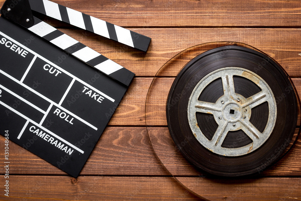 Screenwriter desktop with movie clapper board wooden background top view