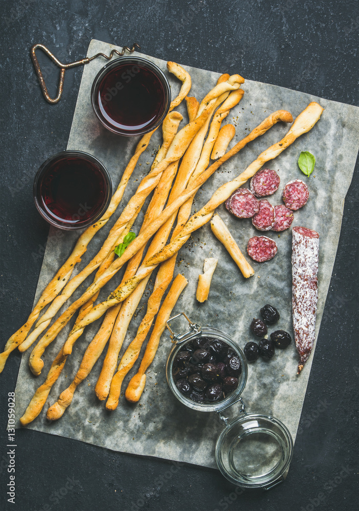 Wine and appetizers set. Italian Grissini bread sticks, dry cured pork meat sausage, black olives in