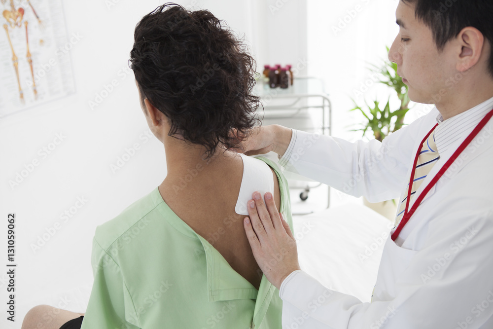 The doctor is putting a compress on the shoulder of a man