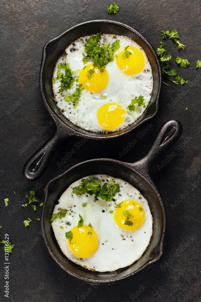 Pans with fried eggs and herbs